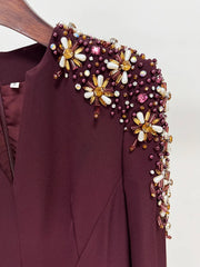 Maroon garment with floral bead embellishments on a plain background