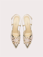 Pair of gold high-heeled shoes with gemstone embellishments on a light gray background