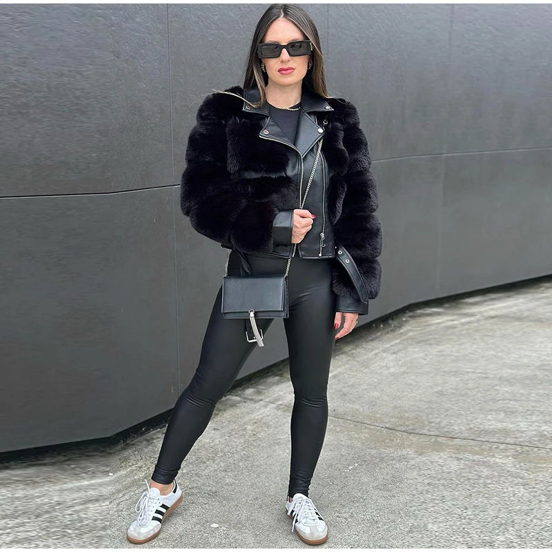 Woman wearing a black fur coat, black leggings, and white sneakers against a gray wall.