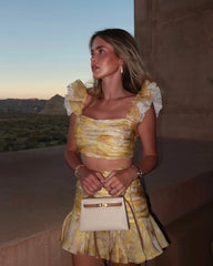 Woman in a yellow dress standing outdoors with a scenic background