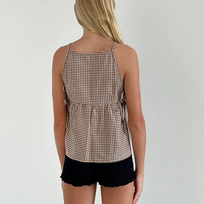 Person wearing a checkered top and black shorts on a plain background