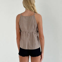 Person wearing a checkered top and black shorts on a plain background