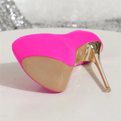 Neon pink high-heeled shoe on a white surface with a blurred background