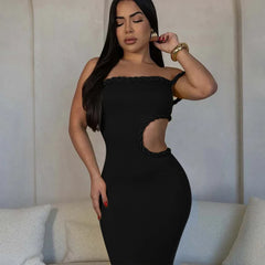 Woman wearing a black dress with cut-out design against a neutral background