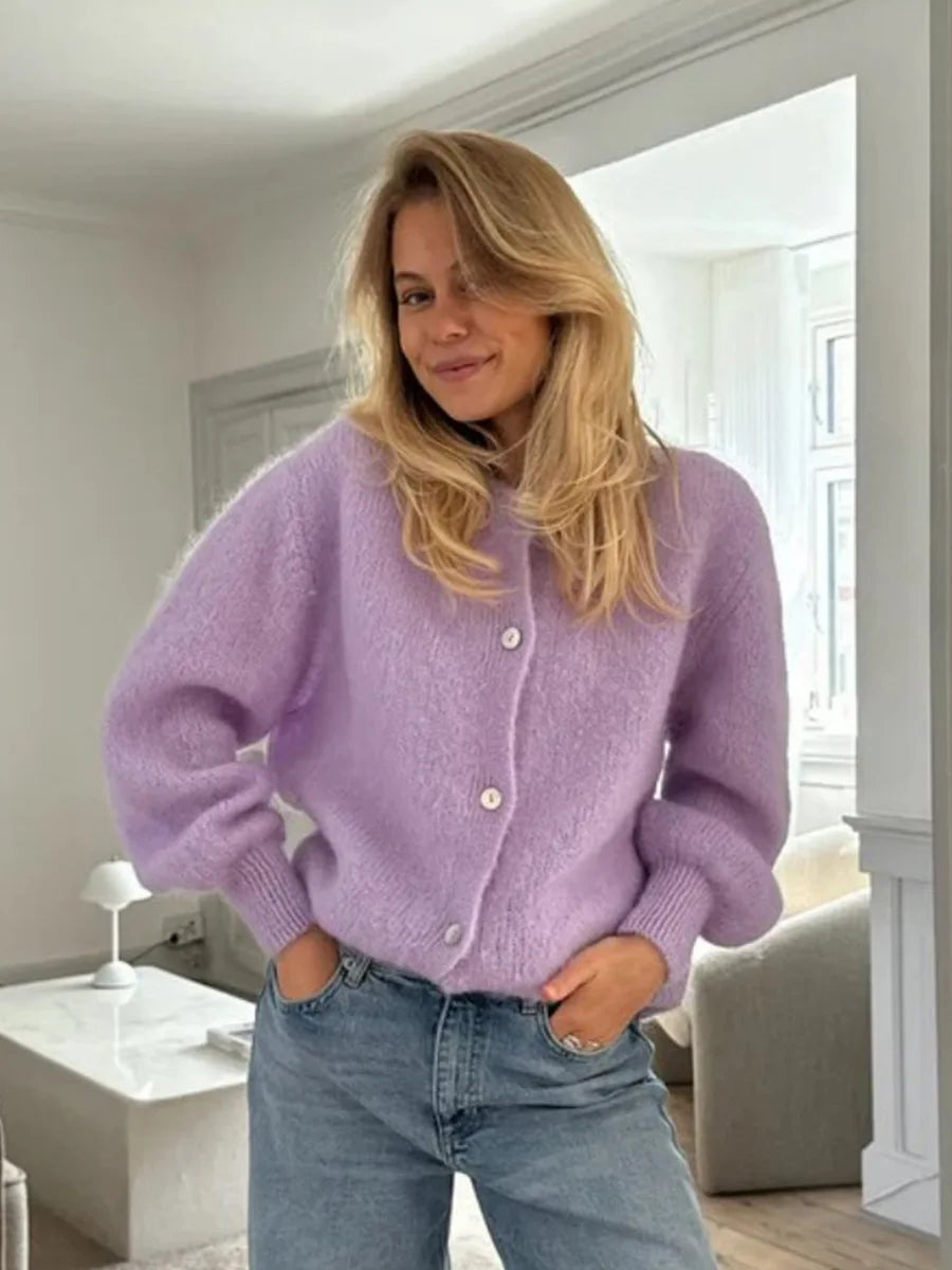 Woman wearing a purple sweater and blue jeans indoors.
