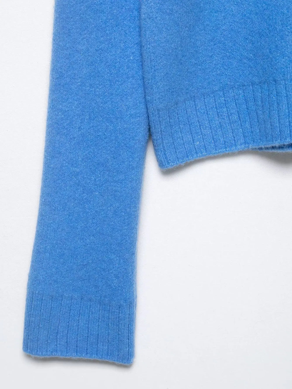 Close-up of a blue sweater sleeve on a white background