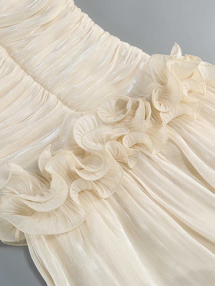 Close-up of a cream-colored dress with ruffled details on a gray background