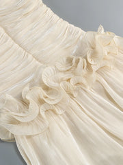 Close-up of a cream-colored dress with ruffled details on a gray background