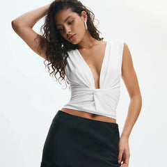 Woman wearing a white top with a deep neckline and black skirt on a light gray background