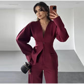 Woman in a burgundy suit taking a mirror selfie in a minimalistic setting