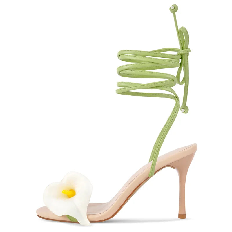 High-heeled sandal with green tie-up strap and white calla lily decoration on a white background