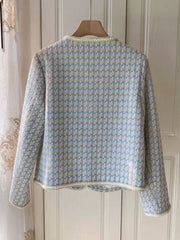 Blue and white patterned jacket on a wooden hanger against a white wall.