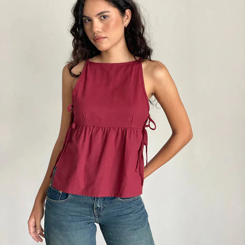 Woman wearing a red sleeveless top with blue jeans on a plain background