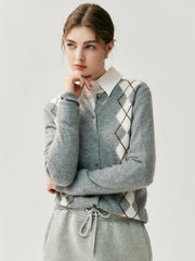 Person wearing a gray argyle sweater over a white shirt on a light background