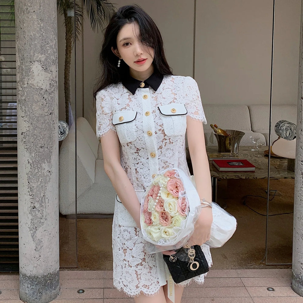Woman in a white lace dress holding a bouquet of flowers indoors.