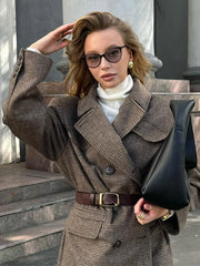 Woman in a brown checkered coat with a black clutch outdoors.