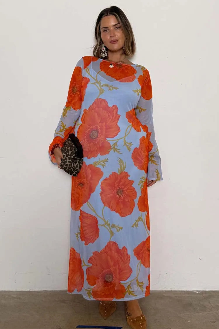 Woman wearing a floral dress with orange flowers on a light blue background.