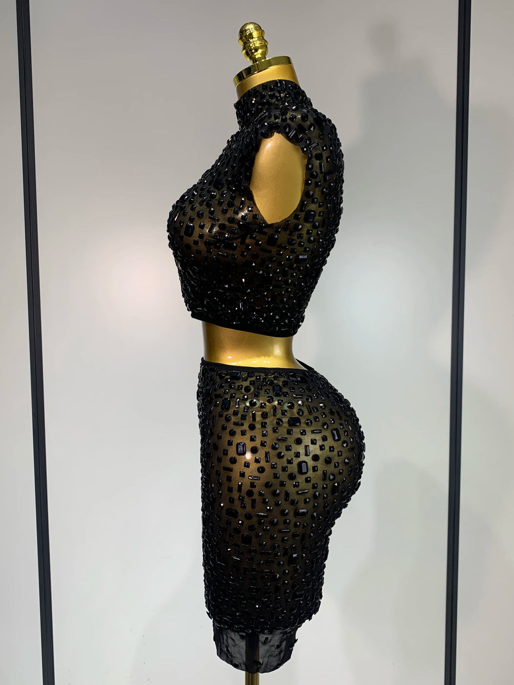 Black beaded two-piece outfit on a mannequin against a neutral background