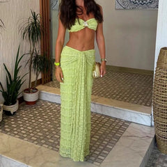 Woman in a green outfit standing in a room with plants and a tiled floor.