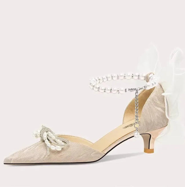 Beige high-heeled shoe with decorative elements on a white background