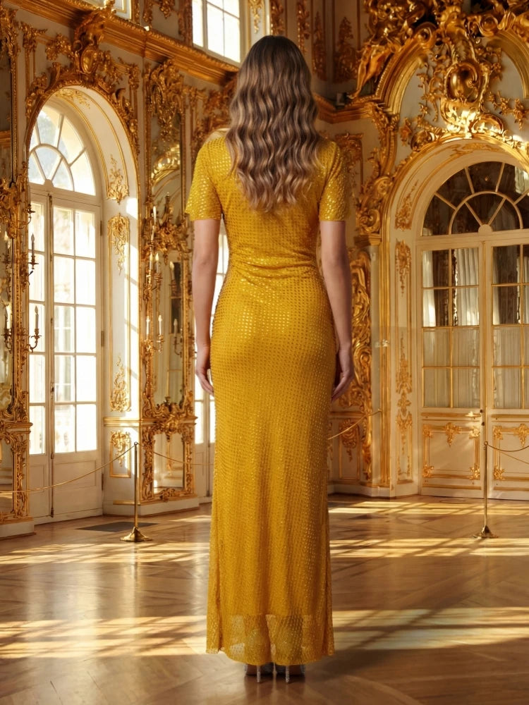 A woman in a gold dress standing in an opulent room with gold decorations.