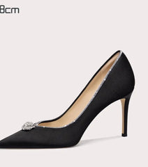 Black high-heeled shoe with a decorative element on a light gray background