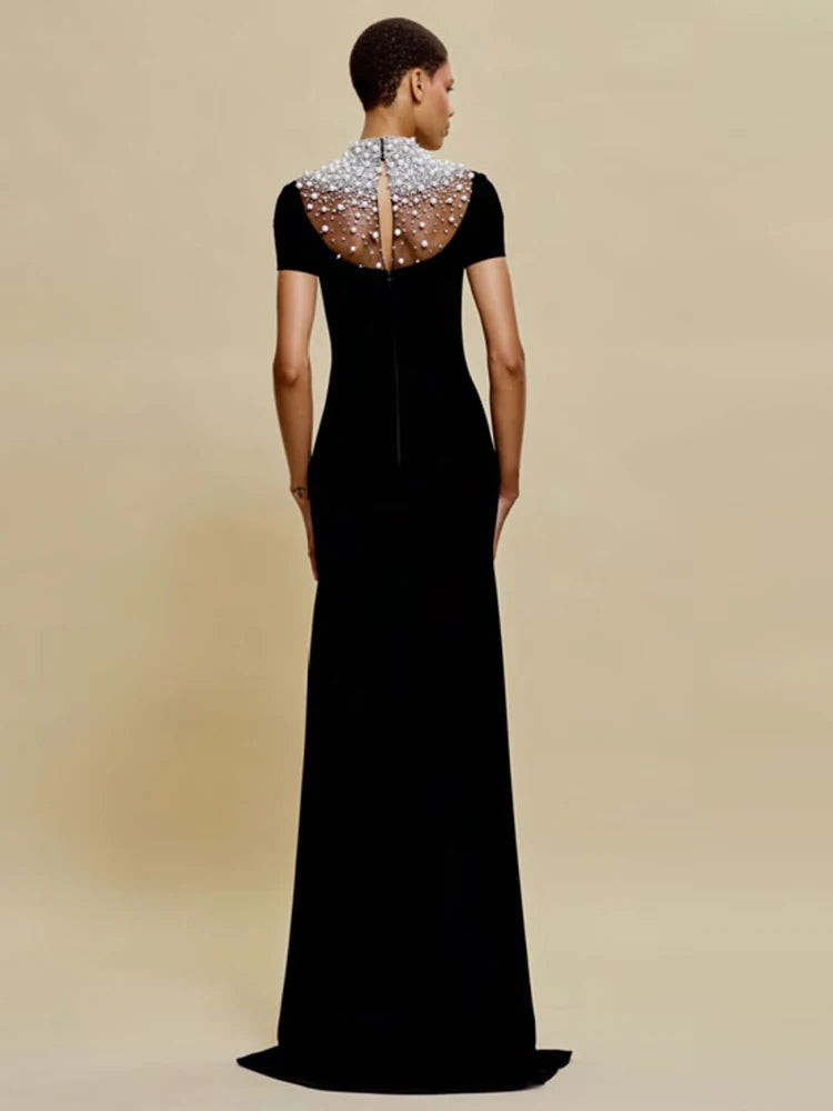 Black evening gown with beaded neckline on a beige background