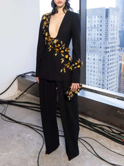 Person wearing a black outfit with gold floral embellishments in an urban setting.