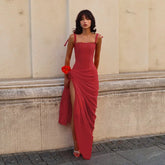 Woman in a red dress standing against a beige wall.