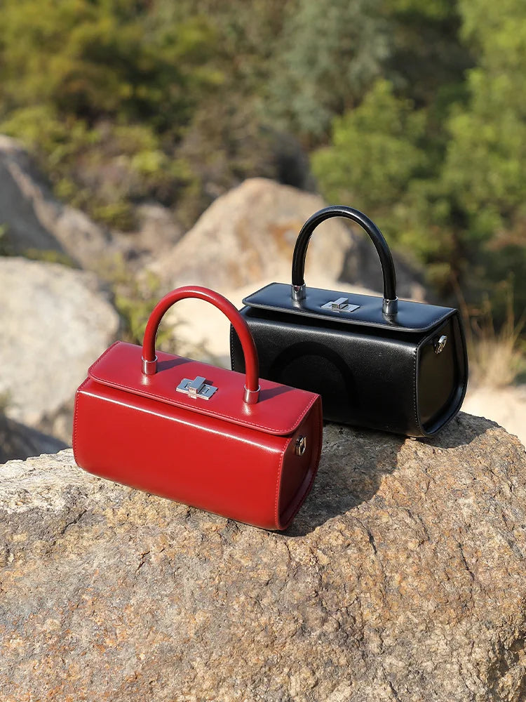 Red and black leather top handle bags on rocks