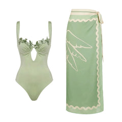 Flat lay of a sage green one-piece swimsuit and a matching patterned sarong.
