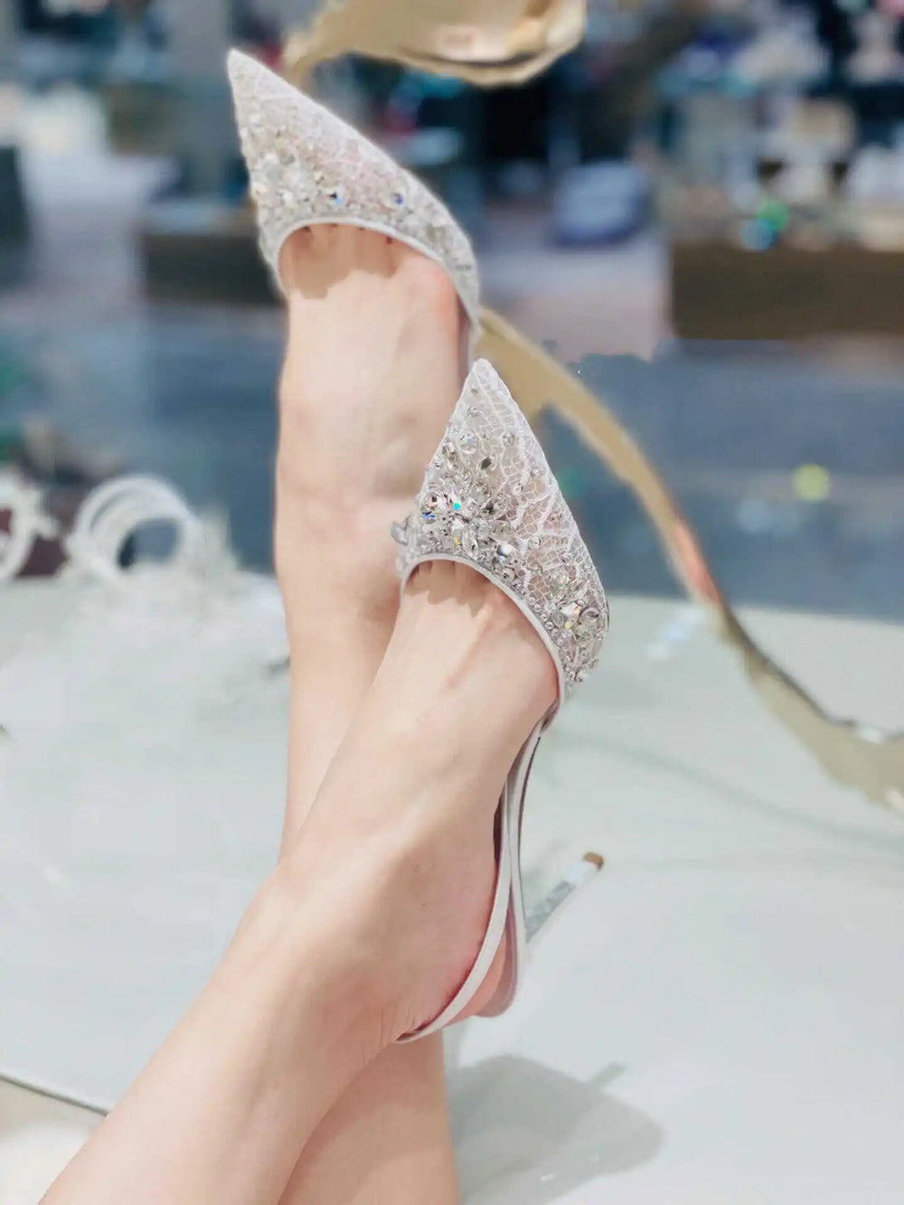 Silver high-heeled shoes with rhinestone details on a blurred background