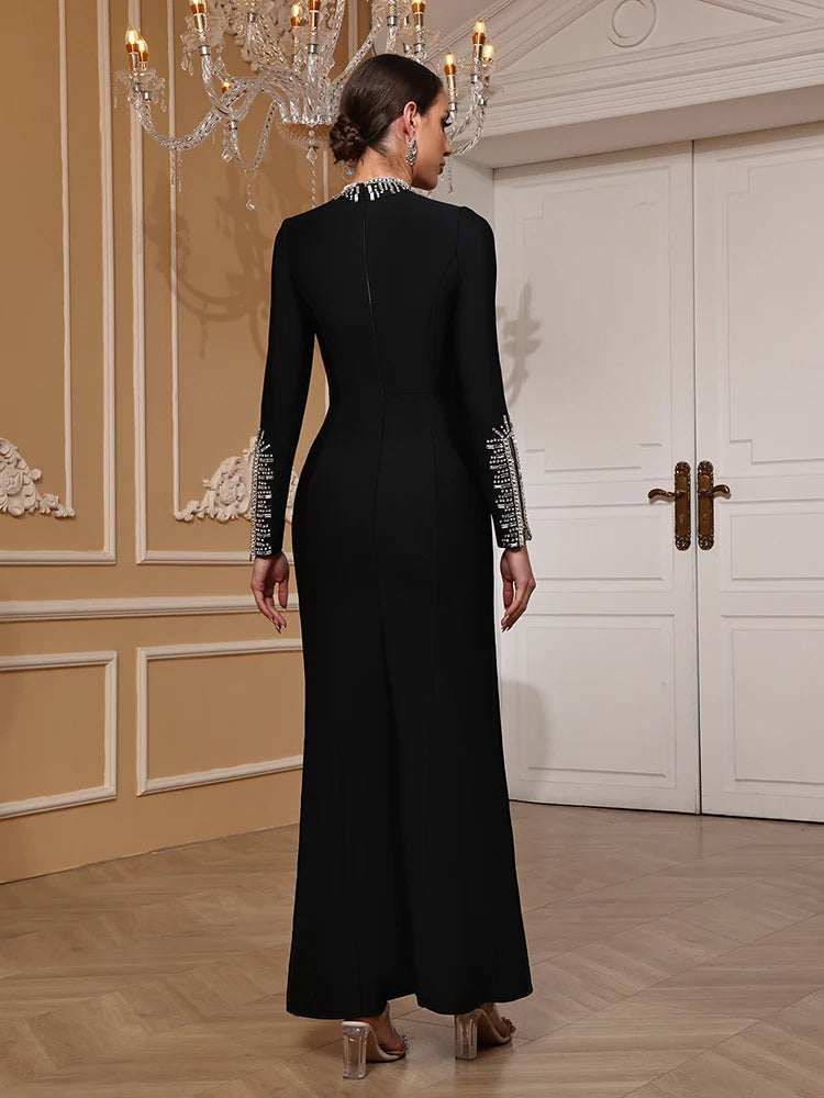 Woman wearing a black evening gown with silver embellishments in an elegant room.