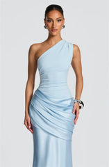 Woman wearing a light blue one-shoulder dress against a plain background