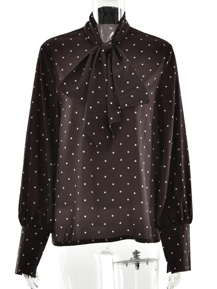 Black blouse with white polka dots and a bow neckline on a mannequin.