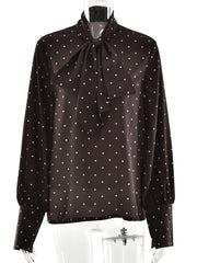 Black blouse with white polka dots and a bow neckline on a mannequin.