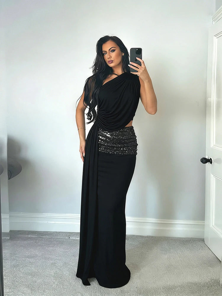 Woman taking a mirror selfie wearing a black evening gown with sequin detailing.