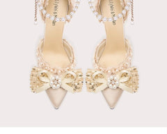 Beige high-heeled shoes with decorative bows and pearls on a white background