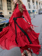 Woman wearing a red dress with black accents on a city street.