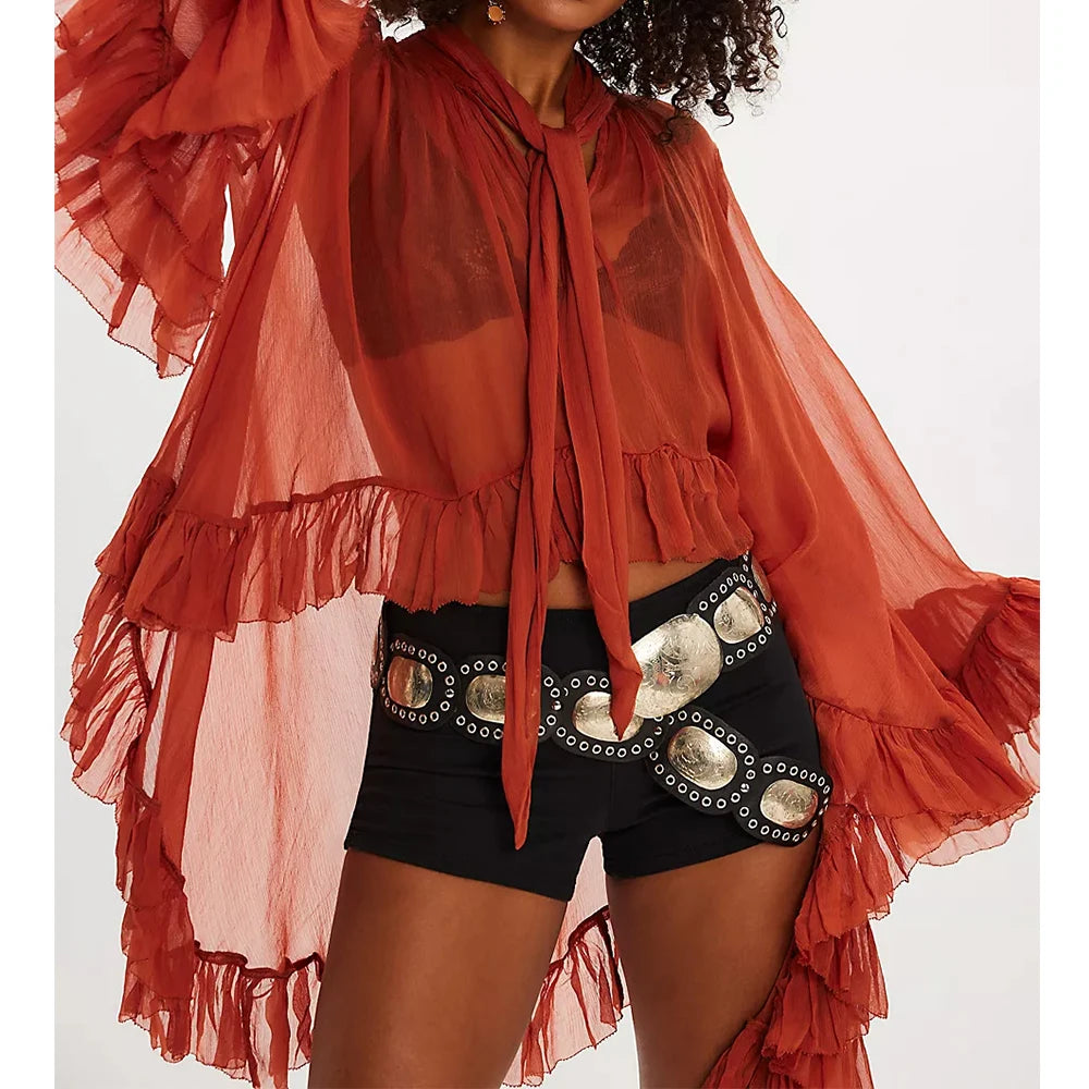 Person wearing a red ruffled top and black shorts with silver embellishments on a white background