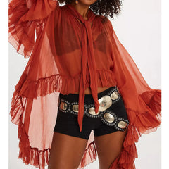 Person wearing a red ruffled top and black shorts with silver embellishments on a white background