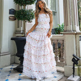 Woman in a white floral dress standing on a porch.