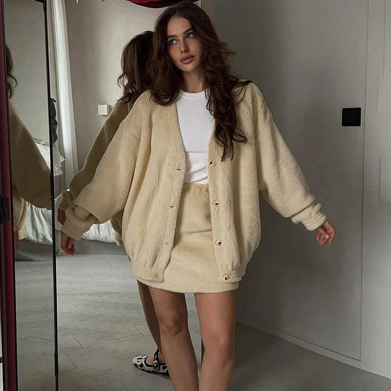 Woman wearing a beige cardigan and skirt in a room.
