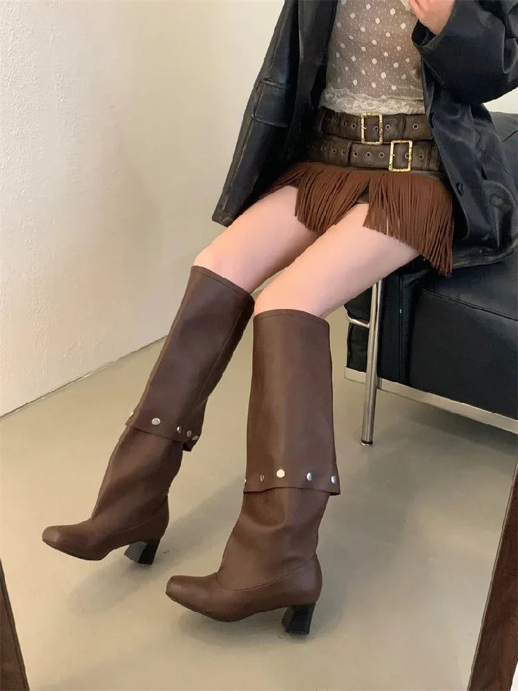 Person wearing brown knee-high boots sitting on a chair.
