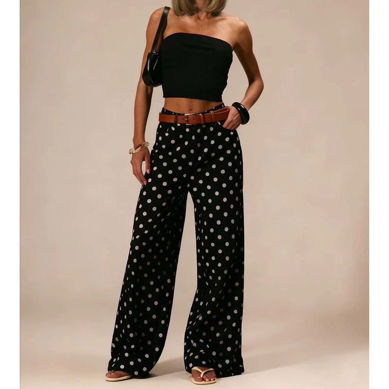 Woman wearing a black strapless top and polka dot pants against a beige background