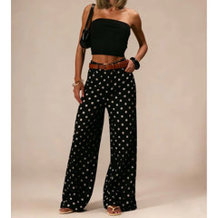 Woman wearing a black strapless top and polka dot pants against a beige background