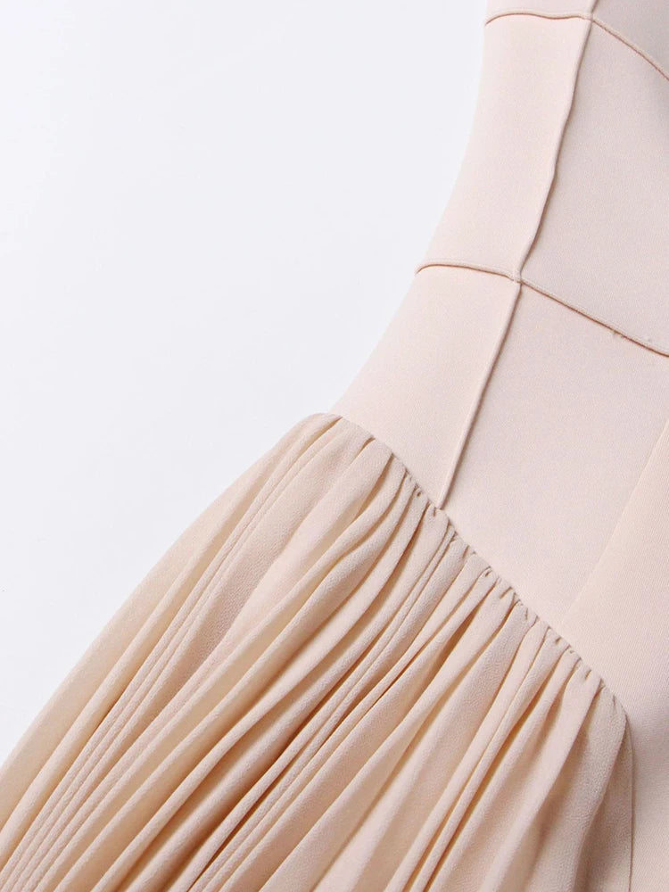 Close-up of a beige dress with pleated skirt on a light gray background