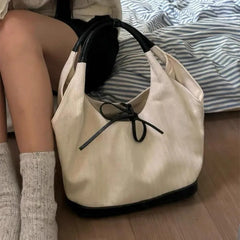 Beige handbag with black accents on a wooden floor