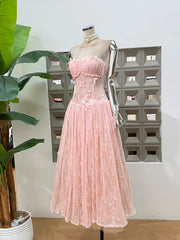Pink lace dress on a mannequin against a geometric wall pattern