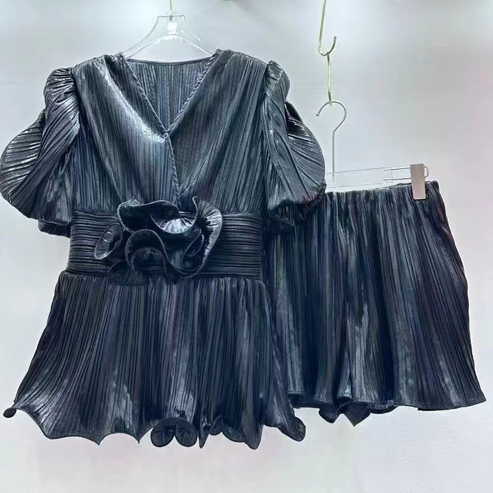 Black pleated dress with matching shorts on hangers against a white background